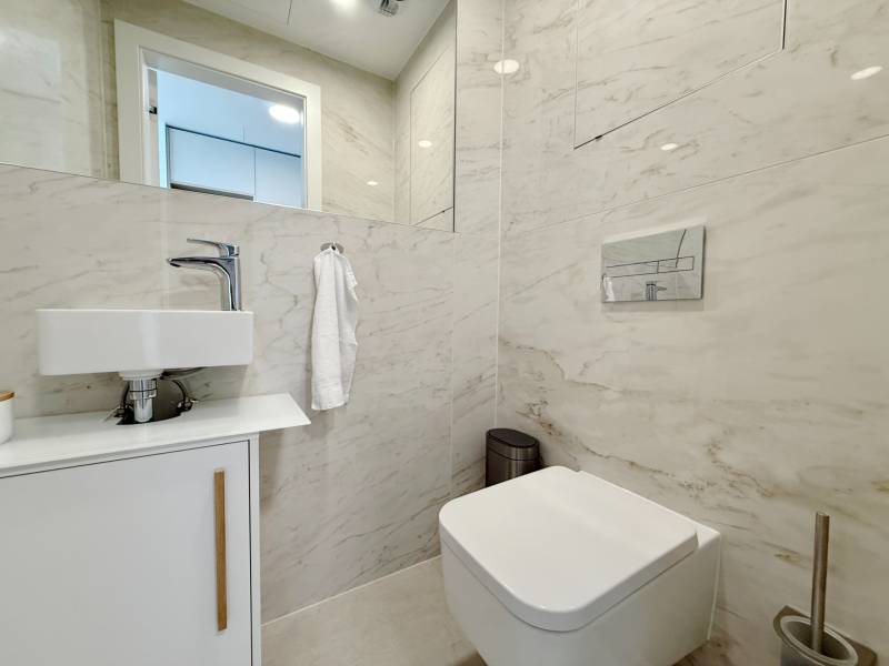 A bathroom in a 3-room apartment with a sink, toilet, and marble tiles.