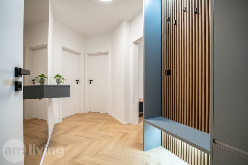 A hallway in a 3-room apartment with a wooden decor floor and wardrobe cabinets.