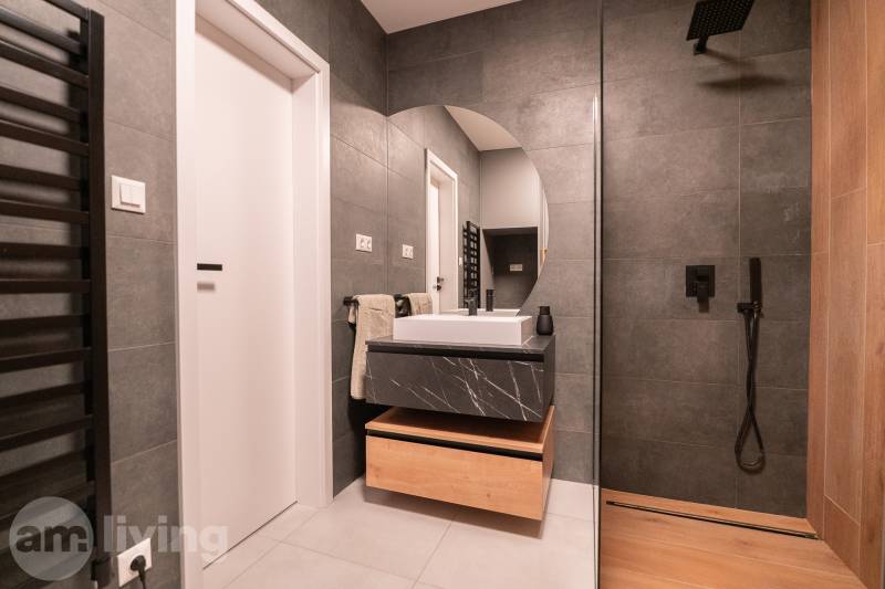 Bathroom with a shower, ceramic tiles, and a sink in a 3-room apartment.