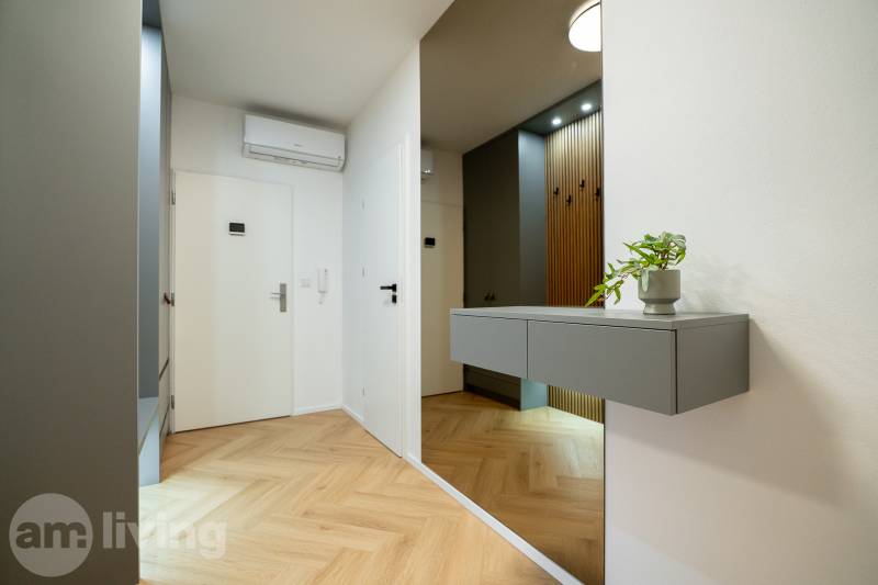 Entrance hallway in a 3-room apartment with a wooden decor floor and a gray cabinet.