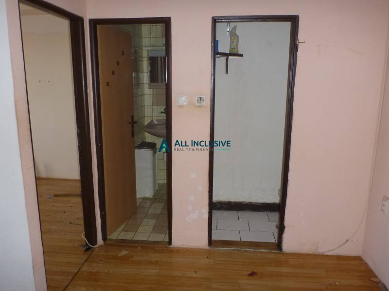 Interior of a two-room apartment with a wooden decor floor and a view of the bathroom.