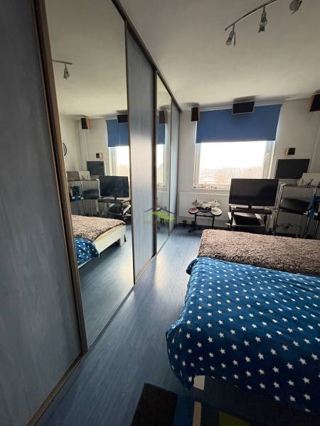 A bedroom in a 3-room apartment with a work corner and built-in wardrobes.
