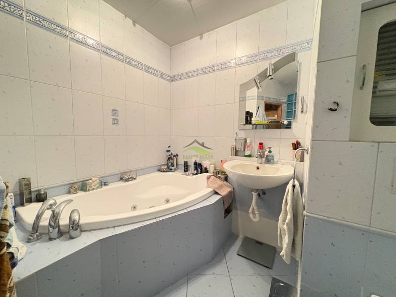 A bathroom with a corner bathtub and a sink in a 3-room apartment.