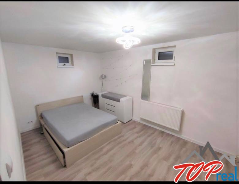 Bedroom in a family house with a bed, dresser, and wooden decor flooring.