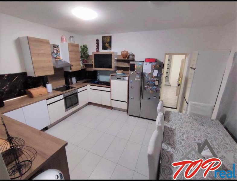 A kitchen in a family house with a wooden decor, white appliances, and a dining table.