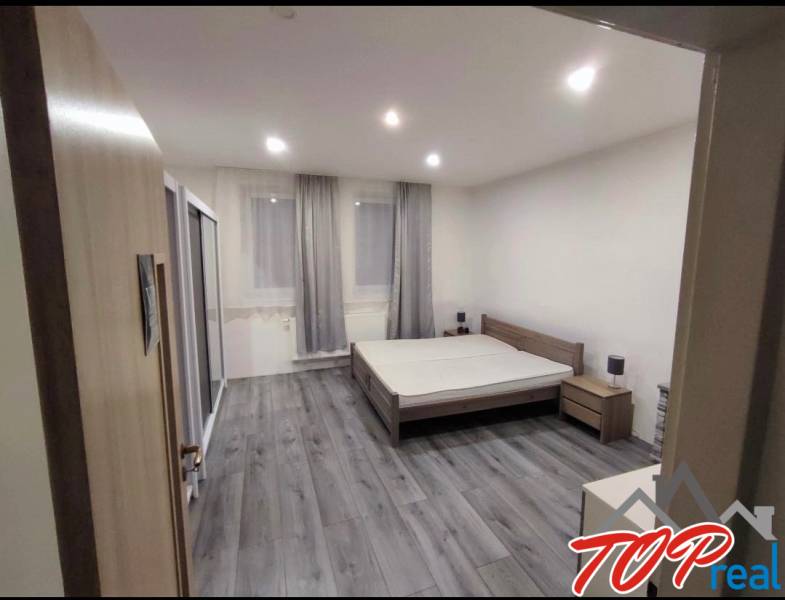 A bedroom in a family house with a wood-patterned floor and large windows.