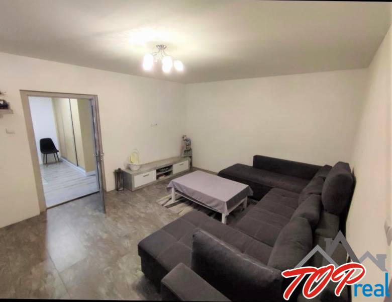 Living room in a family house with a corner sofa and a table, floor with wooden decor.