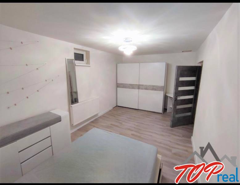 A bedroom with white furniture and a wood-patterned floor in a family house.