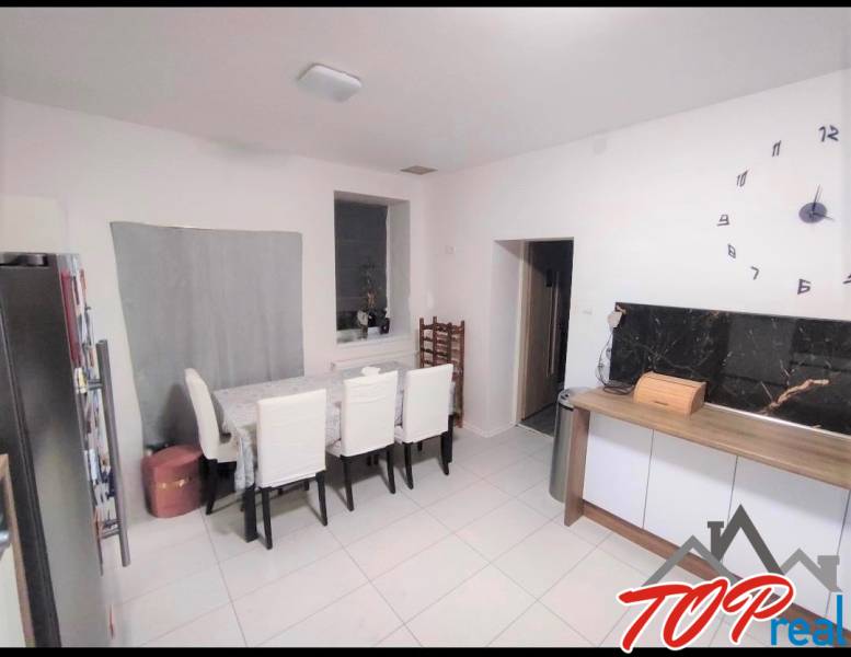 Dining room in a family house with a large clock and upholstered chairs.