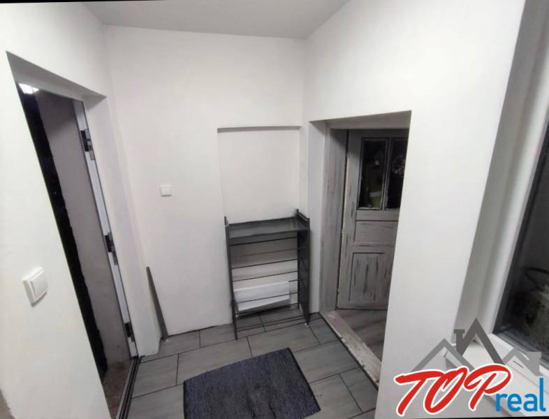 The interior of a family house with tiled flooring and white walls leads to wooden doors.