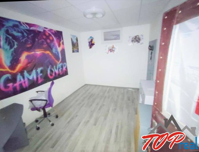 A room with a video game theme and a wooden decor floor in a family house.