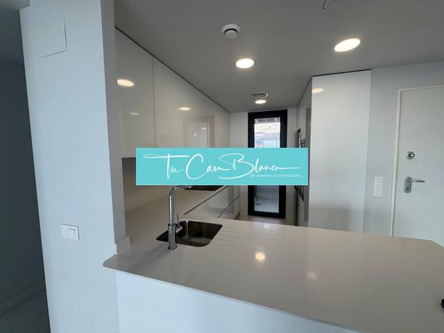 A kitchen in a 3-room apartment with glossy white cabinets and a large work space.