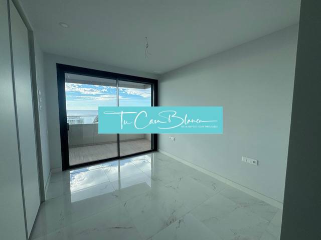 An empty room with a white ceramic floor and a large window in a 3-room apartment.