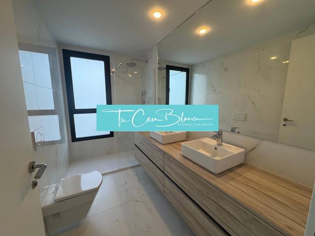 A bathroom in a 3-room apartment with a shower and wooden decor on the sink.