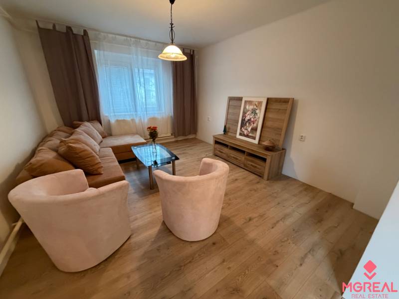 Living room with a corner sofa, glass table, and floor with wood decor.