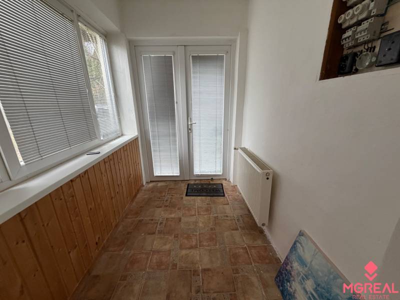 Family house with a glass corridor, tiles, and a radiator, entrance door with blinds.