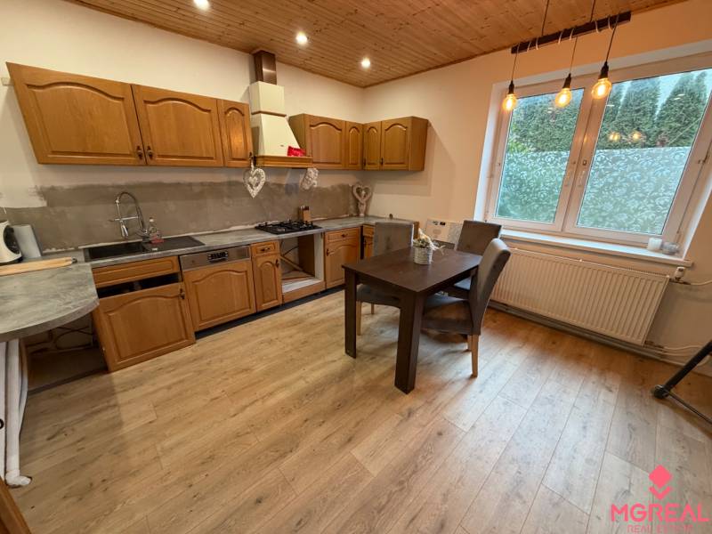 A kitchen in a family house with wooden cabinets and a wooden decor floor.