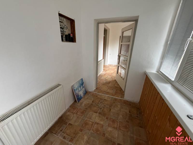 The hallway of a family house with a radiator and light-colored walls, tiled floor.