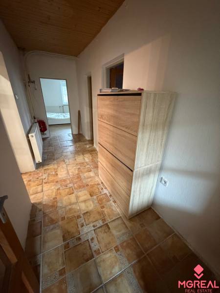 A hallway in a family house with a tiled floor and a wooden ceiling.