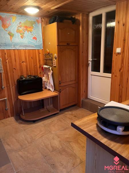 A room in a family house with wooden walls, a map on the wall, and kitchen appliances.