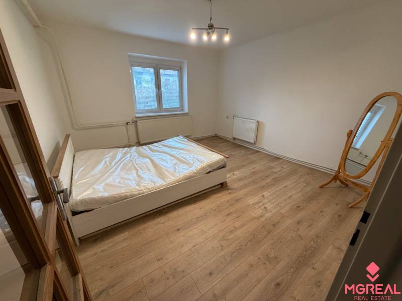 Bedroom of a family house with a double bed and a wooden decor floor.