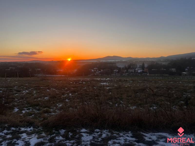 Sunset over family houses in Tvrdomestice with hills in the background.
