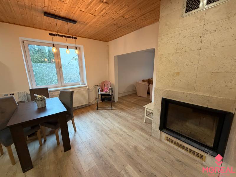 Dining room in a family house with a window, fireplace, and floor with wood decor.