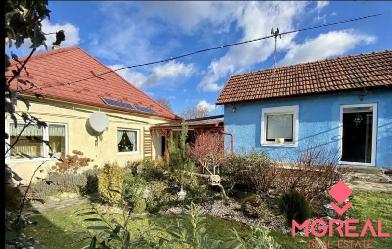 A family house in Tvrdomestice with two colorful houses, a garden, and a solar panel.