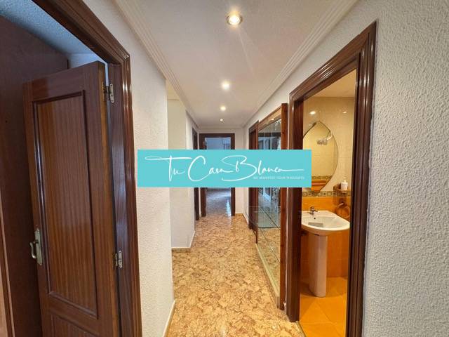 A corridor in a 4-room apartment with doors and a view of the bathroom.