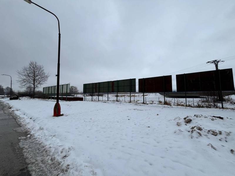A snowy plot in Poprad with commercial spaces and abandoned advertising panels.