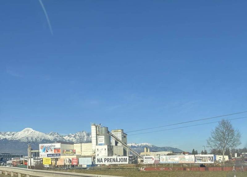 Commercial spaces in Poprad with a backdrop of snow-covered mountains and a clear sky.