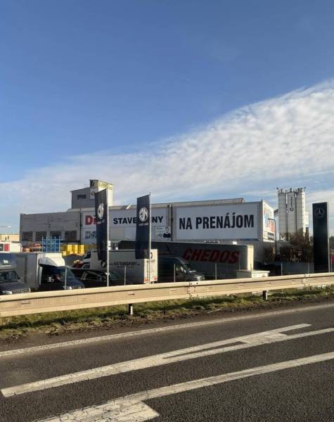 Commercial premises in Poprad with building materials and cars in the background of the highway.