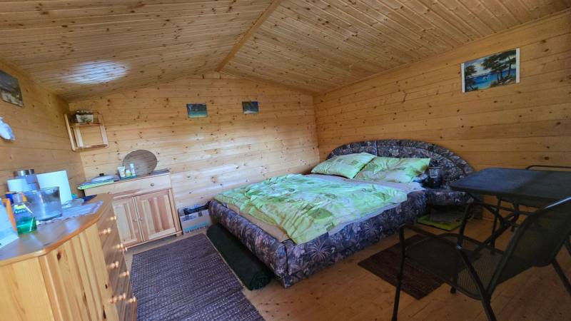 Interior of a wooden cabin with a double bed, a wardrobe, and wall decorations.