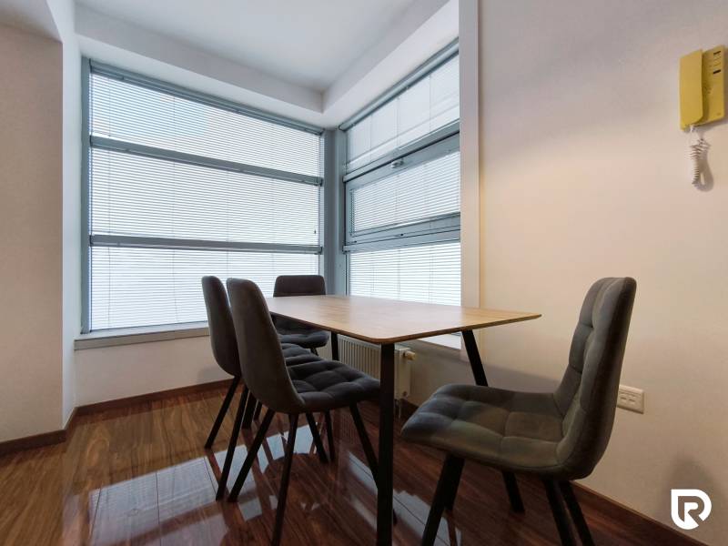 Dining room with a table and chairs in a two-room apartment, floor with wooden decor.