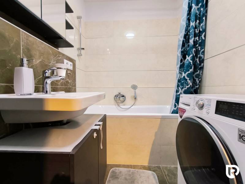 Bathroom with a shower bath, sink, and washing machine in a 2-room apartment.