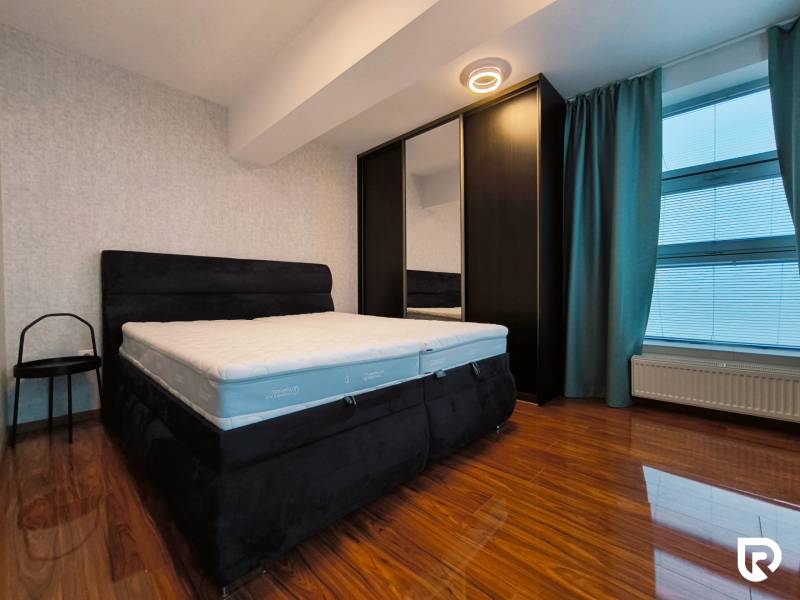 Bedroom in a 2-room apartment with a bed, wardrobe, and floor with a wooden decor.