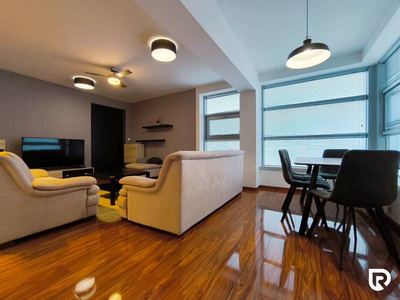Living room with wood-patterned flooring, sofas, television, and dining table in a two-room apartment.