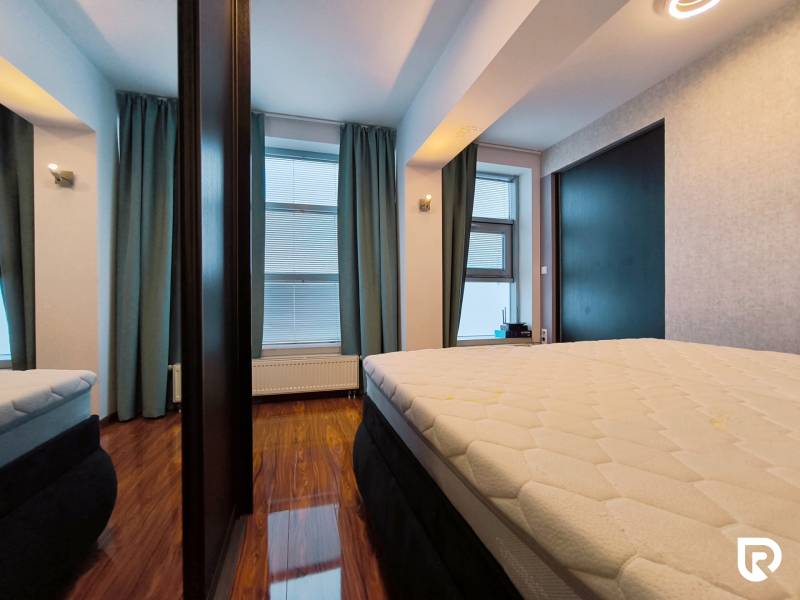 Bedroom in a 2-room apartment with a mirror, curtains, and a floor with a wooden decor.