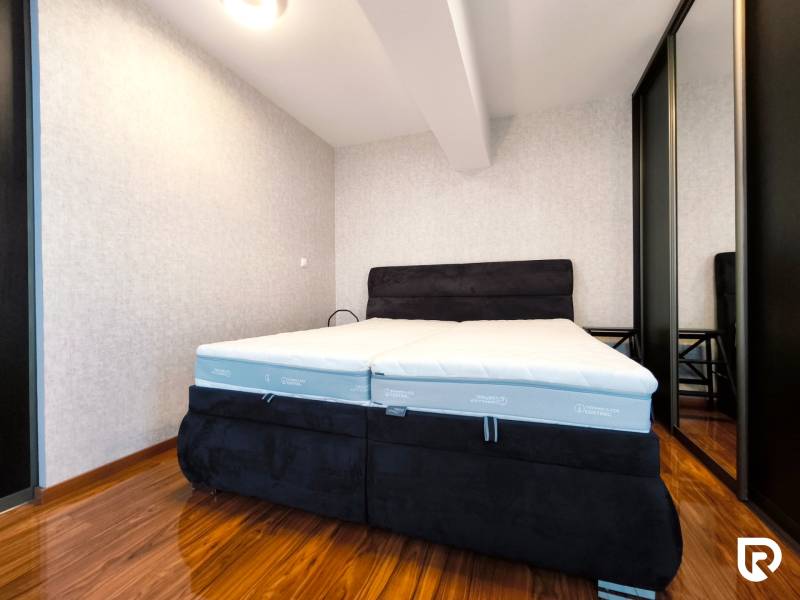 Bedroom in a 2-room apartment with a comfortable bed and wardrobe, floor with wooden decor.