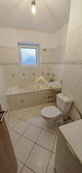 A bathroom in a 2-room apartment with a bathtub, toilet, and sink in light shades.