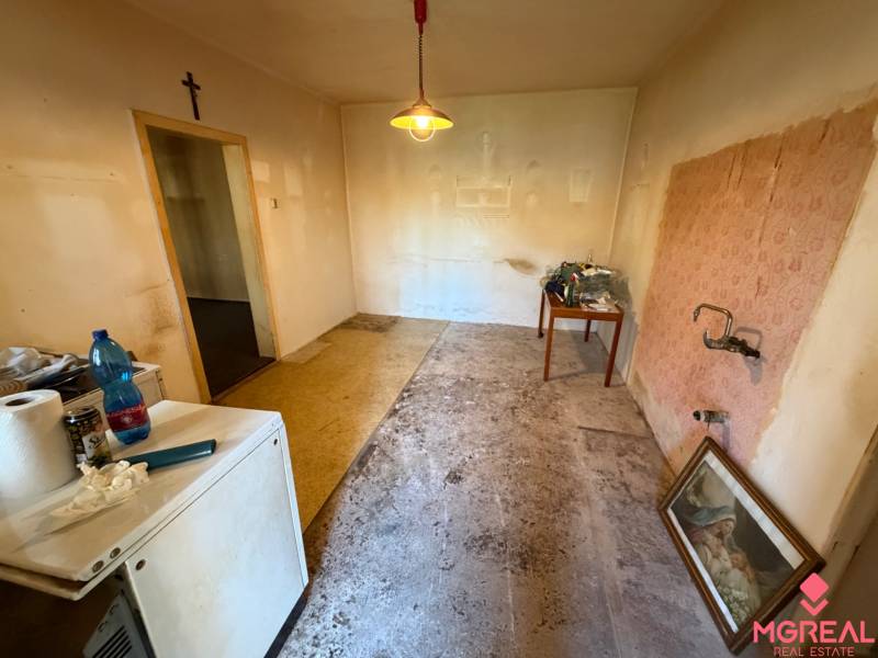 Interior of a family house with an empty room, a table, older furniture, and a dismantled floor.