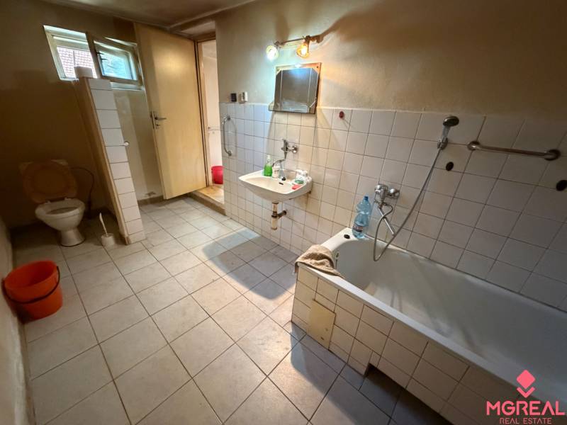 A bathroom in a family house with a bathtub, toilet, and sink on a tiled floor.