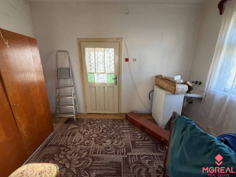 Interior of a family house with a carpet, ladder, and door with a lace curtain.