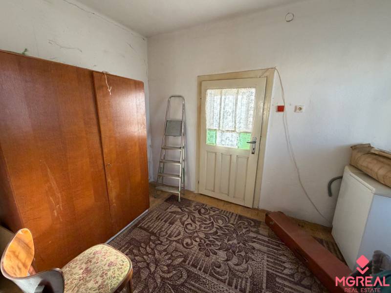 A room in a family house with a carpet, a wooden wardrobe, and a ladder.