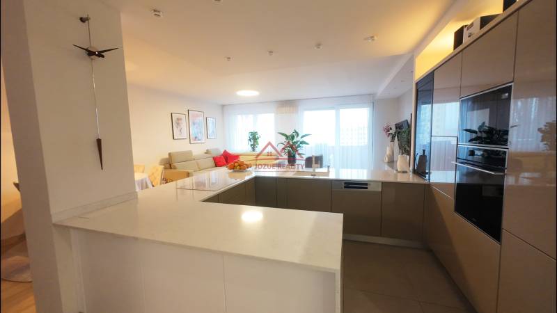 A kitchen corner in a 4-room apartment with a countertop, appliances, and a bright living room in the background.
