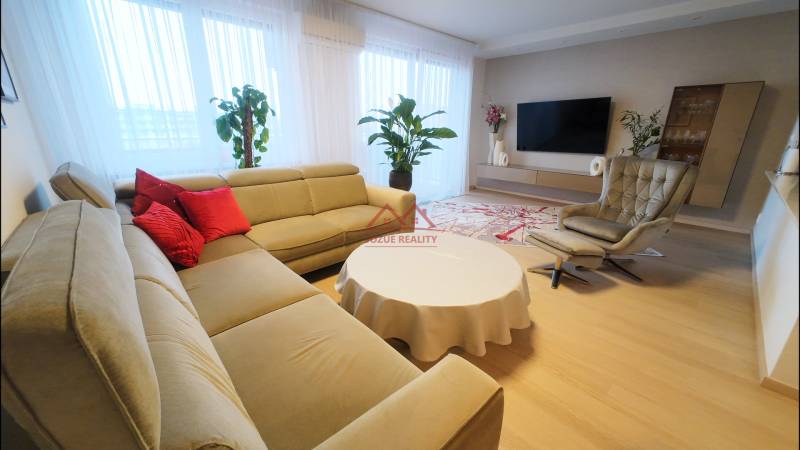 Living room with a beige sofa, red cushions, and a wooden decor floor in a 4-room apartment.
