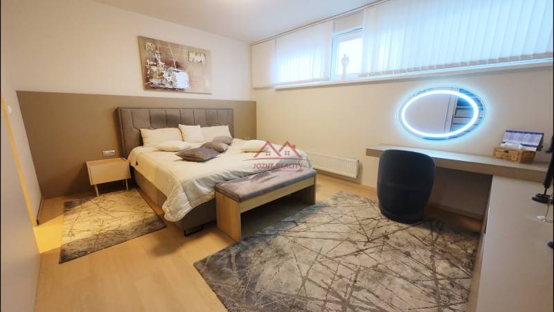 A bedroom with a bed, a mirror, and decorative rugs in a 4-room apartment.