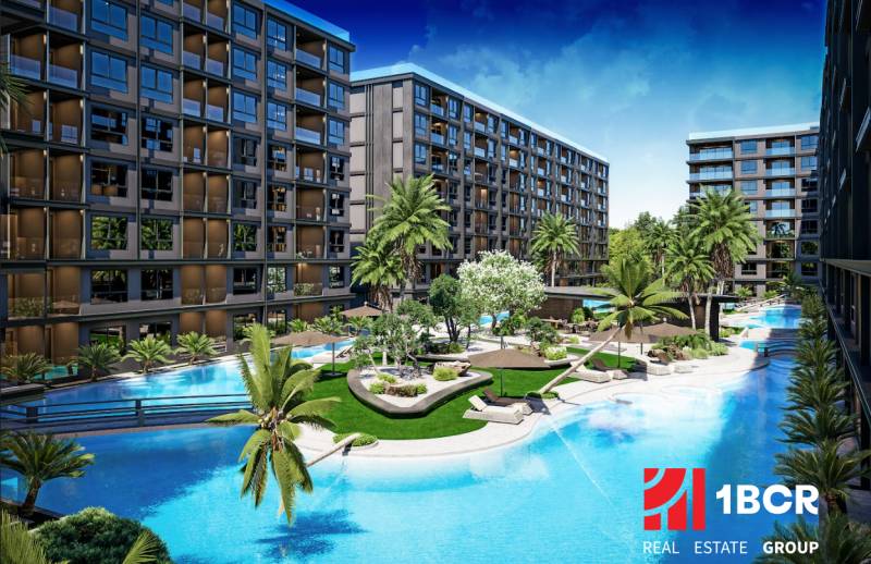 Apartment construction in Pattaya with green areas and a swimming pool among modern buildings.