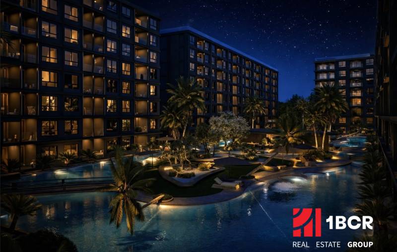 Night construction of apartments in Pattaya with illuminated buildings and a pool.