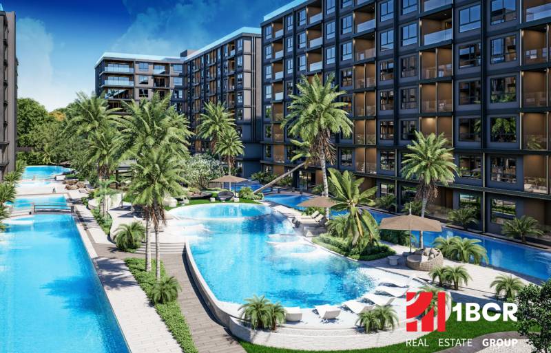 Apartment construction in Pattaya with pools, palm trees, and modern architecture in a tropical setting.